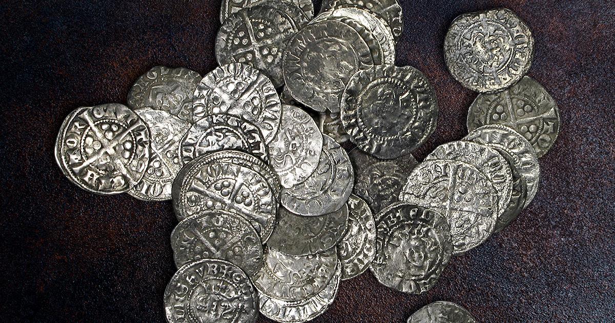 A selection of 13th century silver English pennies is shown on a table.