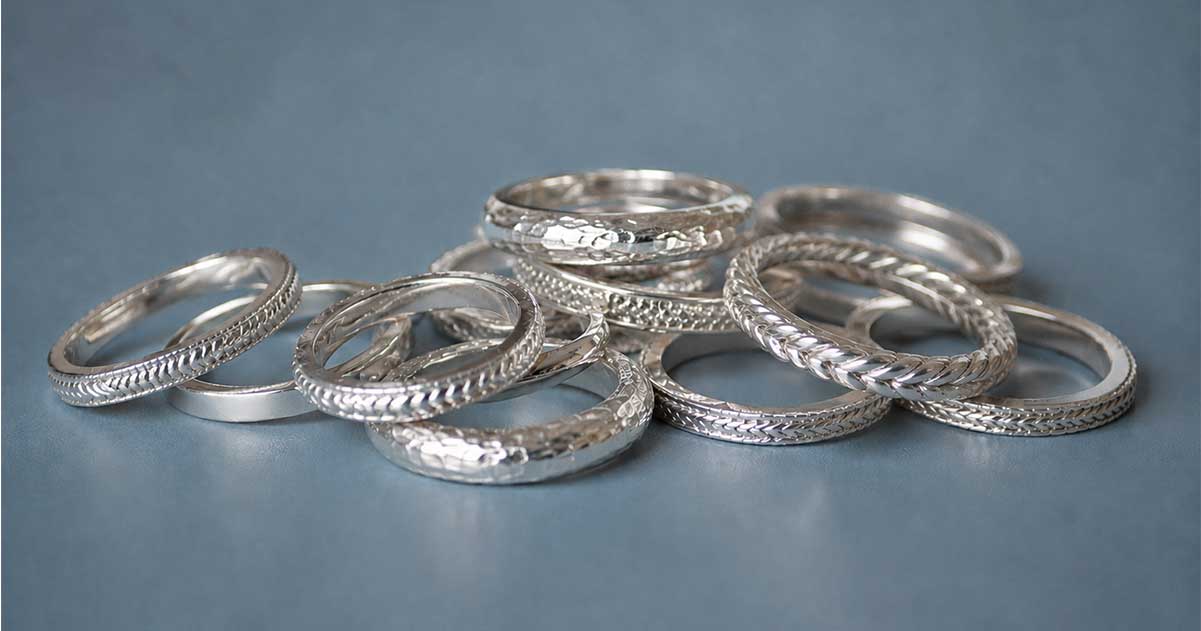A pile of silver rings against a light blue background.
