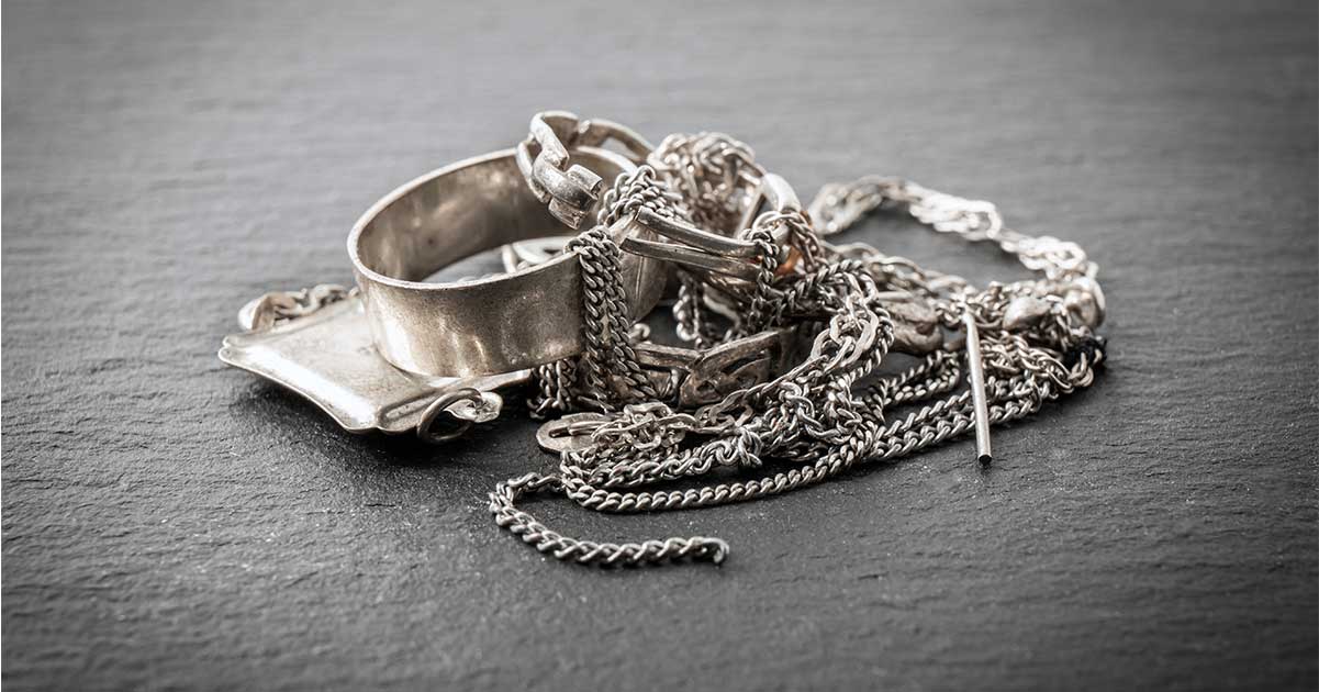 A collection of silver jewelry against a gray background.