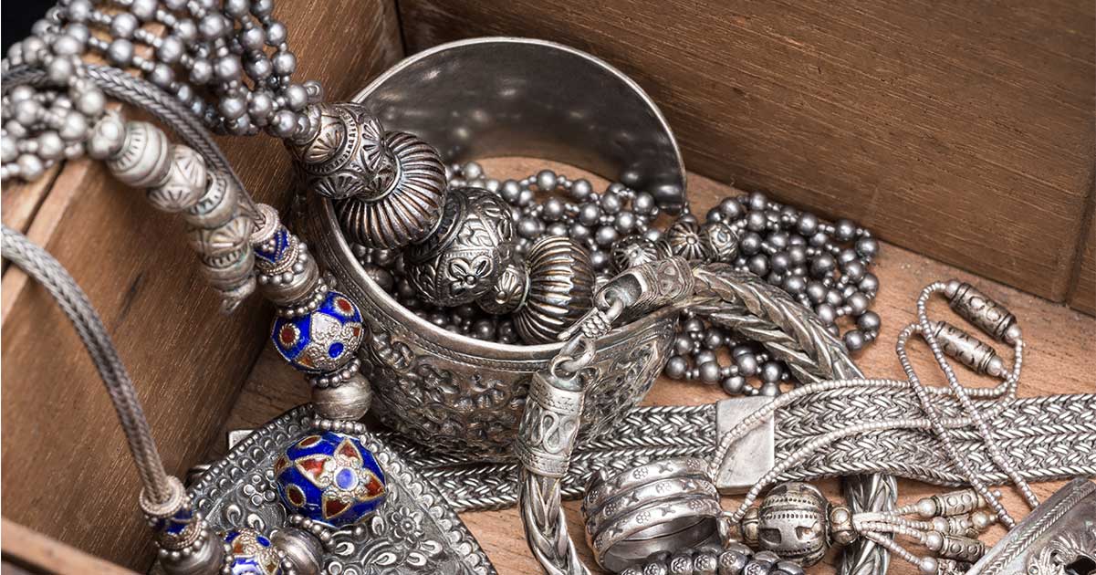 A collection of silver jewelry in a wooden box.
